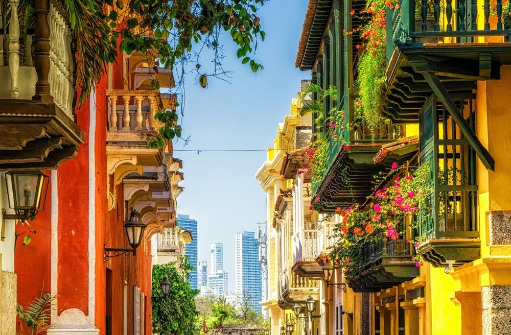 Morocco Imperial Cities — sunlit old-city lane with carved wooden balconies and flowering vines — HauteBlack